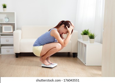 Upset Woman On Weigh Scale At Home, Asian