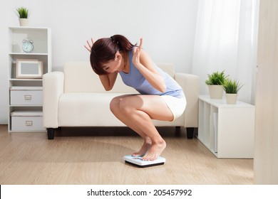 Upset Woman On Weigh Scale At Home, Asian