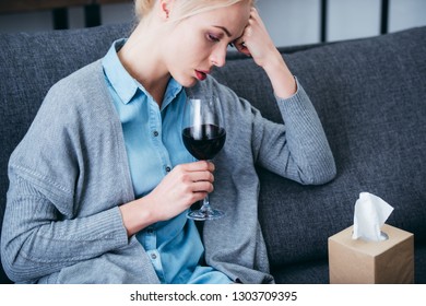 Upset Woman Sitting With Glass Of Red Wine And Tissue Box At Home