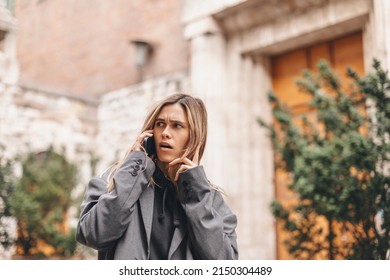 Upset Woman. Woman Talking Sad By The Bad News She Hear On The Cell Mobile Phone. Gloomy Girl Short Hair Wear Grey Suit And Twisting A Lock Of Hair On Her Finger.