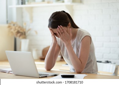Upset woman touching head using calculator and laptop for calculating finance. Frustration young housewife with headache taxing, accounting, statistics and credit analytic for mortgage payment.