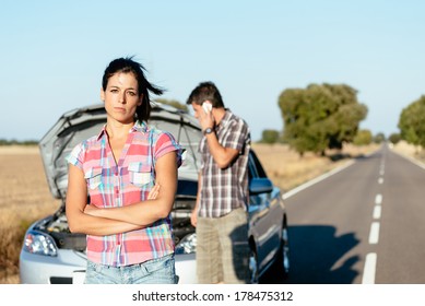 Upset Woman Waiting For Car Help While Man Arguing On The Cellphone With Insurance Service. Couple In Road Trip Problems Because Of Breakdown Engine.