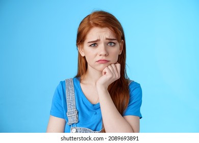 Upset worried cute uneasy goomy redhead girl frowning, pull disappointed face, feel pity embarrassed, lean hand whining, complaining, loosing lottery, stand blue background sorrow - Shutterstock ID 2089693891