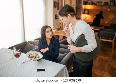 Upset Yougn Businesswoman Complain About Bowl With Salad. She Hold It In Hands And Point. Customer Look At Waitress. Young Woman In White Blouse Is Upset.