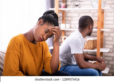 Upset Young African Couple Sitting On Sofa Ignoring Each Other