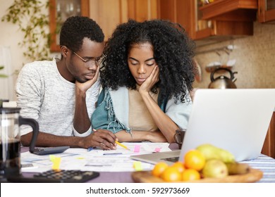 Upset Young African-American Couple Feeling Unhappy Because They Can't Afford Buying New Car, Facing Financial Problem And Economic Crisis, Trying To Solve Troubles, Reviewing Their Finances At Home