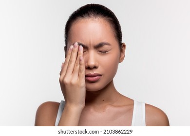 Upset young asian woman suffering from strong eye pain, touching her eye and crying over white studio background, closeup photo, copy space. Healthcare, eye disorders and diseases concept - Shutterstock ID 2103862229