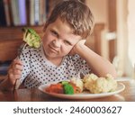 Upset, young boy and reject food at dinner table for not eating vegetable and no to nutrition at home. Healthy, child and face with disgust for portrait or refuse balanced diet for fussy eater