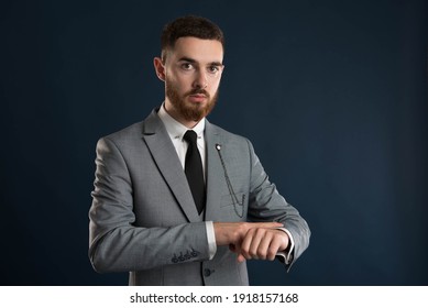 Upset young businessman checking the time wearing a grey suit and black tie