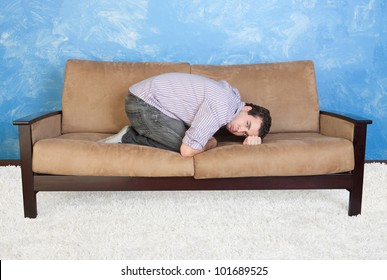 Upset Young Caucasian Man In Fetal Position On Sofa