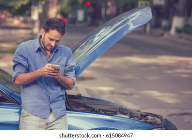 Upset young man calling texting roadside assistance after breaking down