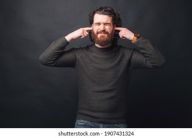 An Upset Young Man Is Covering His Ears Because Is Too Noisy There .