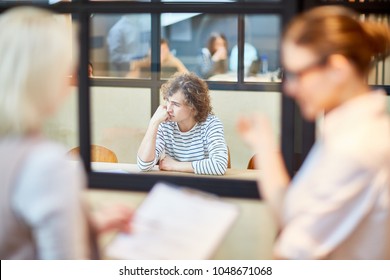 Upset Young Man Sitting By Desk In Boardroom And Being Nervous About Decision Of Employers After Interview