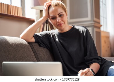 Upset young woman crying and putting her head on the hand while looking at the laptop screen at her psychologist - Powered by Shutterstock