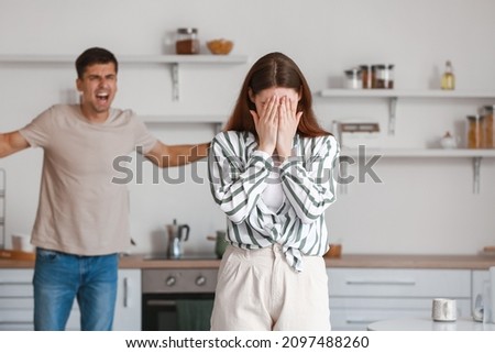 Upset young woman during quarreling with her husband in kitchen