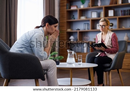 Upset young woman has counseling session with female psychologist in the office, telling her about problems. Psychologist taking notes on clipboard. Psychology, mental therapy, mental health
