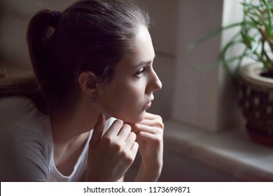 Upset young woman look far in window thinking about personal troubles, sad female feeling blue after breakup with lover or boyfriend, hurt offended girl grieve at home having relationships problems