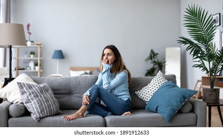 Verärgerte junge Frau, die über Probleme nachdenkt, allein auf dem Sofa zu Hause sitzt, psychologisches Problem.