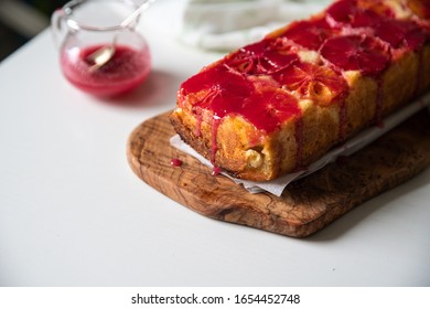 Upside Down Blood Orange Pound Cake On Olive Tree Board And Orange Tulips Bouquet On White Wooden Table.