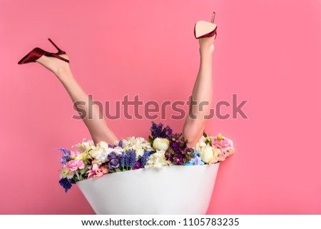 upside down of female legs in high heeled shoes and skirt with beautiful flowers isolated on pink 