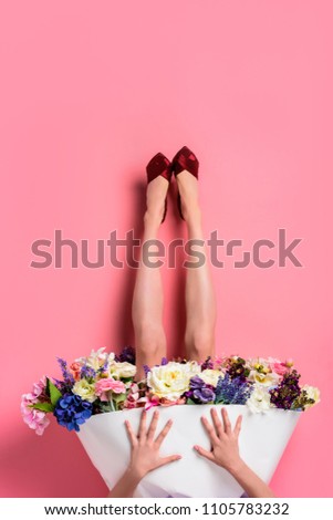 upside down of girl in high heeled shoes and skirt with beautiful flowers isolated on pink 
