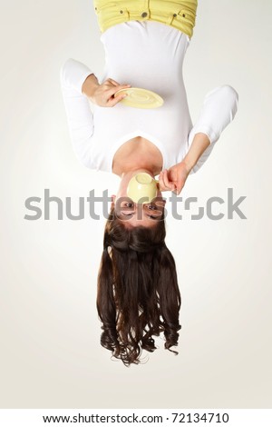 Upside down view of young girl drinking tea on white background