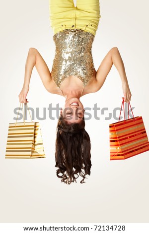 Upside down view of young girl with paperbags on white background