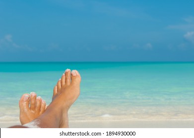 Upside Woman's feet relaxing on beach against the blue turquoise ocean