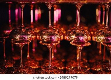 Upside-down wine glasses with vibrant pink and gold reflections creating a luxurious atmosphere - Powered by Shutterstock