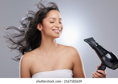 The upsides to being a brunette are clear. Studio shot of a beautiful young woman blowdrying her hair.