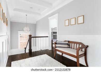 An Upstairs Hallway In A Luxury Home With A Coffered Ceiling, Dark Hardwood Floor, A Wooden Bench, And Board And Batten Walls.