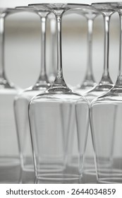 Upturned empty clean glasses on mirror surface against blurred background, closeup