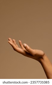 Upturned hand of biracial woman on brown background with copy space. Femininity, body, skin and beauty, unaltered.