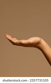 Upturned hand of biracial woman on brown background with copy space. Femininity, body, skin and beauty, unaltered.