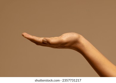 Upturned hand of biracial woman on brown background with copy space. Femininity, body, skin and beauty, unaltered.