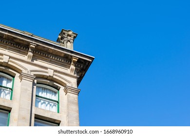 Upward corner view of an old ornate victorian style stone building set against a beautiful blue sky.