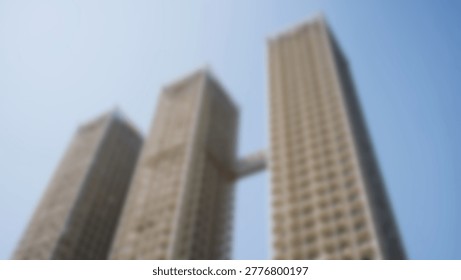 An upward perspective captures the imposing height of modern skyscrapers against a clear blue sky, showcasing urban architecture.