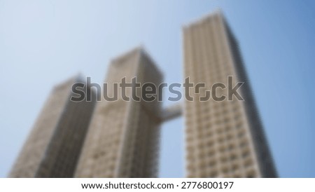 An upward perspective captures the imposing height of modern skyscrapers against a clear blue sky, showcasing urban architecture.