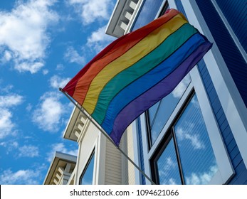 Upward view of gay pride, LGBT flag handing outside of a house