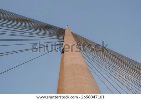 Upward view of modern cable-stayed bridge with geometric lines and clear sky, minimal architectural composition