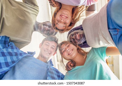 Upward View Of Multi Ethnic Group Of Happy Teenagers Smiling To The Camera.