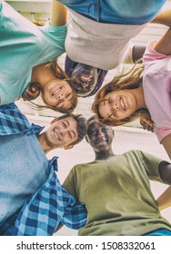 Upward View Of Multi Ethnic Group Of Happy Teenagers Smiling To The Camera.