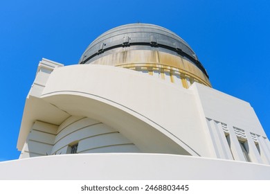 Upward view of the side dome of Griffith Observatory set against clear blue sky