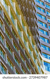An upward-looking, angled perspective of two intersecting skyscraper facades, highlighting the contrast between beige and brown textured architectural elements.