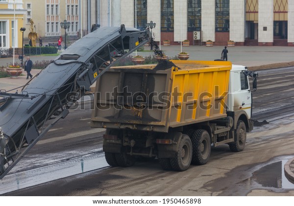 \
Uralsk, Kazakhstan (Qazaqstan), 19.05.2016:\
removal and dismantling of old asphalt, scraper removes old asphalt\
and loads into a truck, road works, road repairs inside the city,\
ремонт дорог