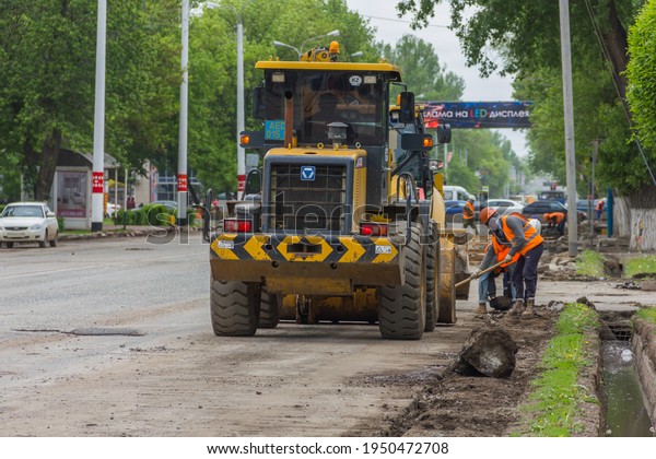Uralsk, Kazakhstan (Qazaqstan), 19.05.2016: repair and\
improvement of the city, repair of the road and curb, road workers\
near the loader, repair of the road in the city, ремонт и\
благоустройство 
