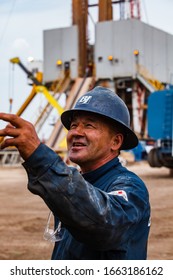 Uralsk Region, Kazakhstan - May 24 2012: Oil Deposit Zhaikmunai. Smiling Happy Asian Worker On Oil Drilling Rig Blurred Background. Baker Hughes Company.