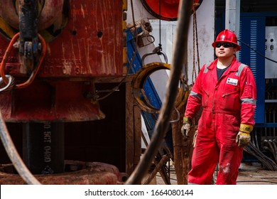 Uralsk region, Kazakhstan - May 24 2012: Oil deposit Zhaikmunai.  Operation of oil drilling rig. Asian worker in Weatherford company red work wear and helmet.