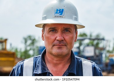 Uralsk Region, Kazakhstan - May 24 2012: Oil Deposit. Portrait Of Serious Posing Caucasian Oil Man Worker. Baker Hughes Company Logo BJ And His Name: Pavel On Hardhat.