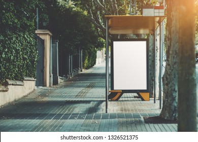 An Urban Bus Stop With Blank Poster Mock-up Inside; An Informational Banner Template Inside Of A Stop Of City Transport On The Sidewalk; Vertical Empty Billboard Placeholder On The Pavement Stone